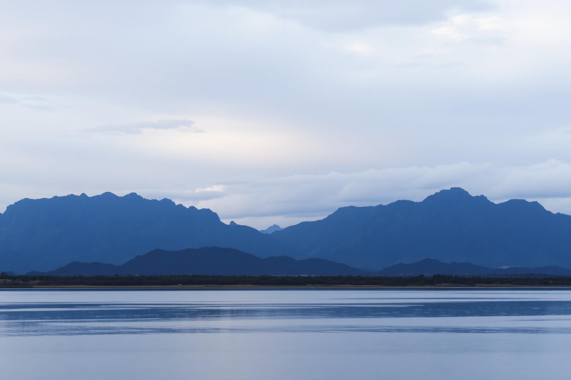 Calm lake with distant mountains at dawn